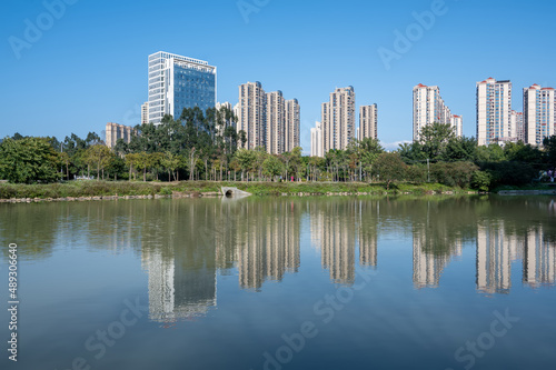 The river reflects the modern city buildings under the blue sky