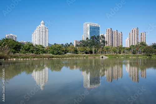 The river reflects the modern city buildings under the blue sky