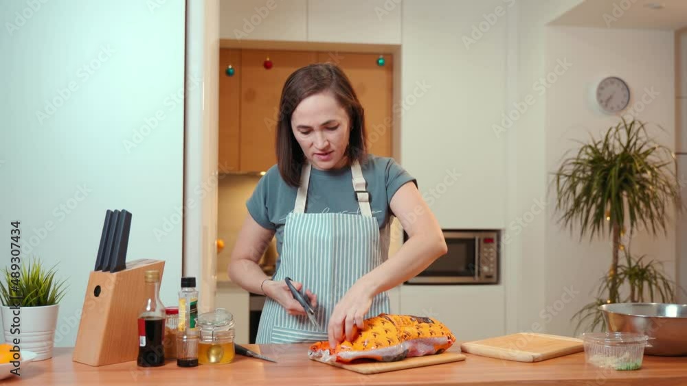 A woman in the kitchen opens a package of duck. Preparing a festive dinner. A woman in the kitchen opens a package of duck. Preparing a festive dinner.