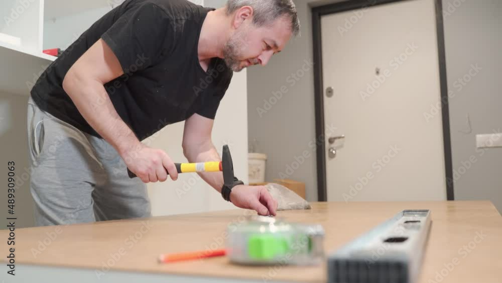 A man hammers nails into the back of a closet. Cabinet assembly. A man hammers nails into the back of a closet. Cabinet assembly.