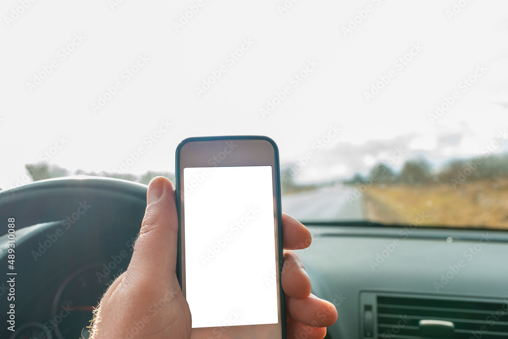 Man using blank white screen mobile smartphone inside a car in spring day landscape. copy space for your advertisement,mockup. Man using blank white screen mobile smartphone inside a car in spring day landscape. copy space for your advertisement,mockup.