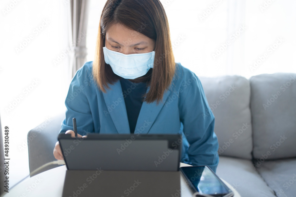 Woman in face mask working from home with her digital tablet Woman in face mask working from home with her digital tablet
