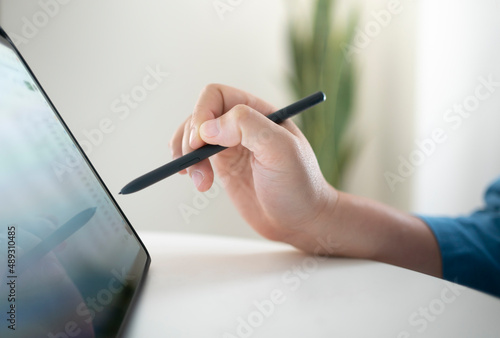 Close up of hand using digital pen on digital tablet