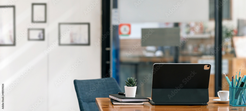 Mockup tablet with magic keyboard on wooden table in office room. Rear view tablet.