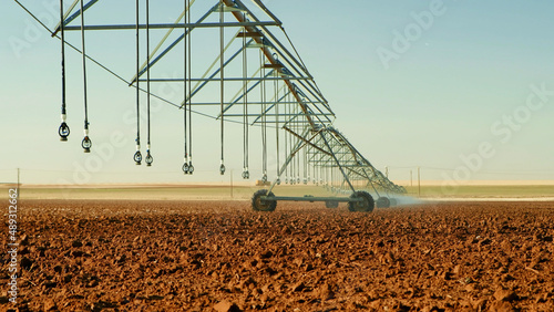 Modern irrigation system sprays water for the new crop at large Texas farm. Center pivot sprinkler mechanism.