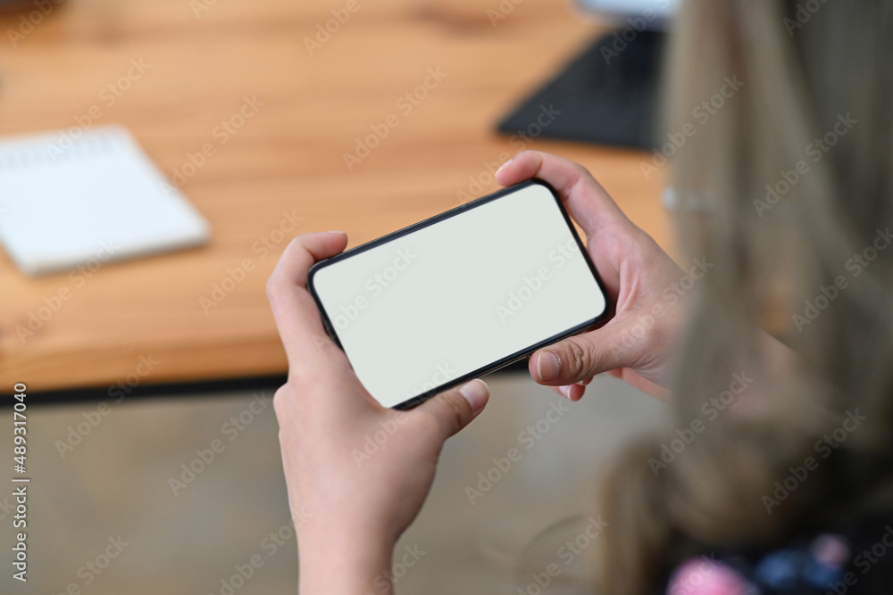 Close up view young woman hands holding smart phone with blank screen horizontally for watching video.