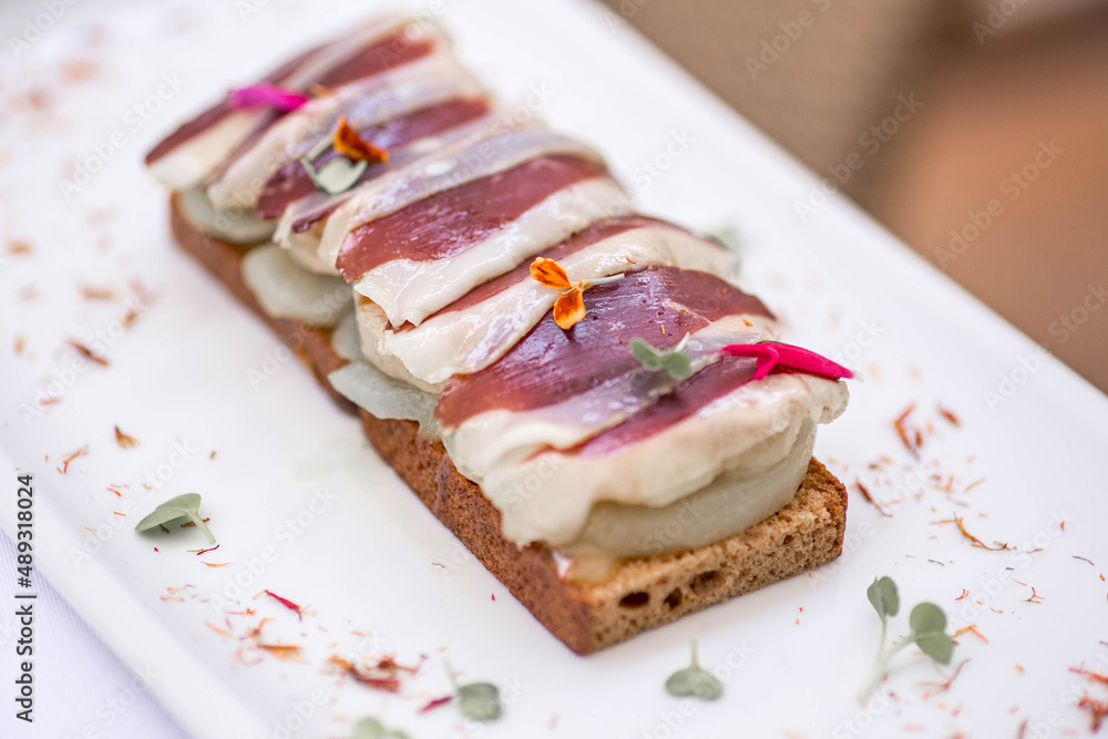 Foie gras with pear and thinly sliced duck breast Magret on the top on the home-made bread. Gourmet appetizer foie gras on a white plate in a restaurant. Duck liver pateTenerife, Spain. Foie gras with pear and thinly sliced duck breast Magret on the top on the home-made bread. Gourmet appetizer foie gras on a white plate in a restaurant. Duck liver pateTenerife, Spain.