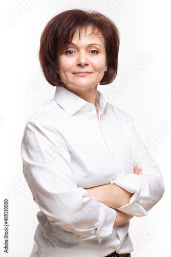 Portrait of Smiling Positive Brunette Mature Confident Caucasian Business Woman in White Shirt Posing With Hands Folded in Front Over White Background.