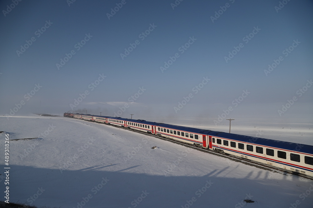 Red diesel train (East express) in motion at the snow covered railway platform - The train connecting Ankara to Kars - Turkey