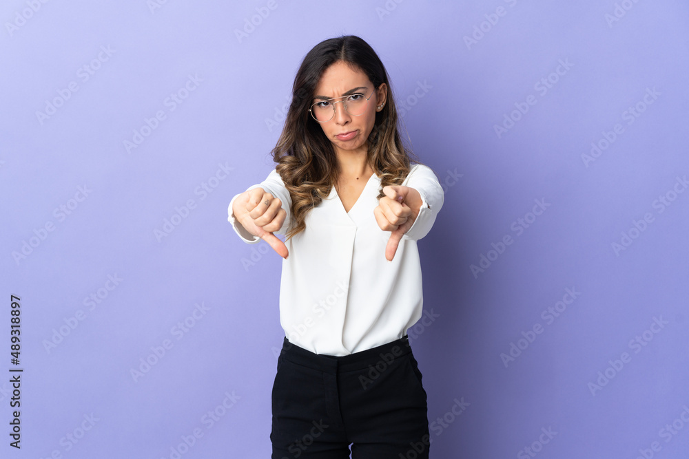 Young caucasian woman isolated on purple background showing thumb down with two hands Young caucasian woman isolated on purple background showing thumb down with two hands