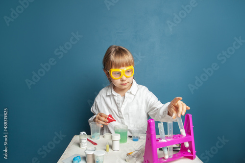 Smart kid student in scientist uniform and glasses studying science