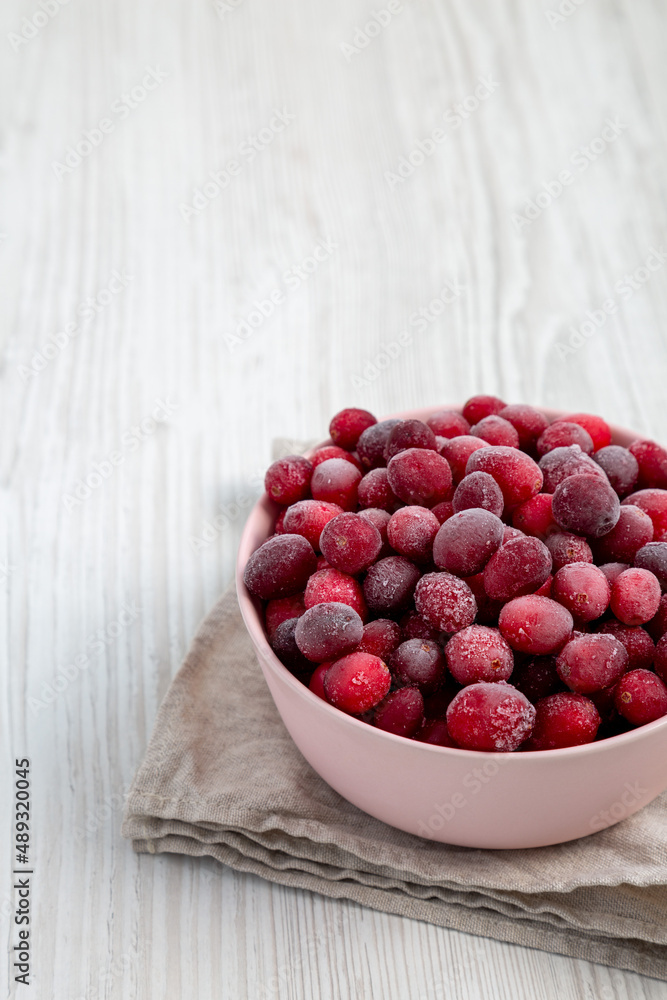Frozen Cranberries in a Pink Bowl on a white wooden surface, side view. Copy space. Frozen Cranberries in a Pink Bowl on a white wooden surface, side view. Copy space.