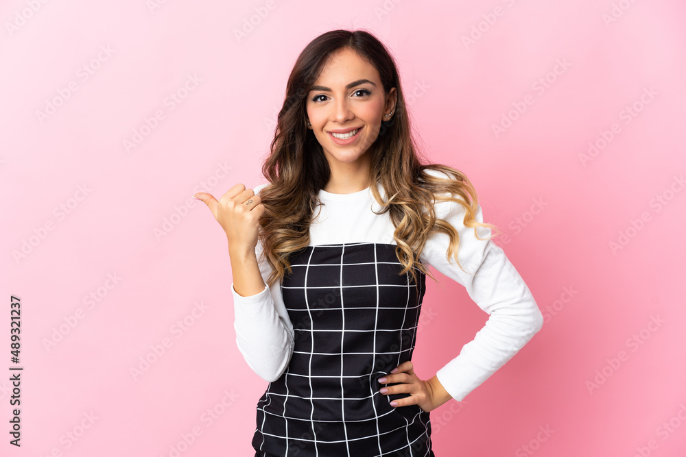Young caucasian woman isolated on pink background pointing to the side to present a product Young caucasian woman isolated on pink background pointing to the side to present a product