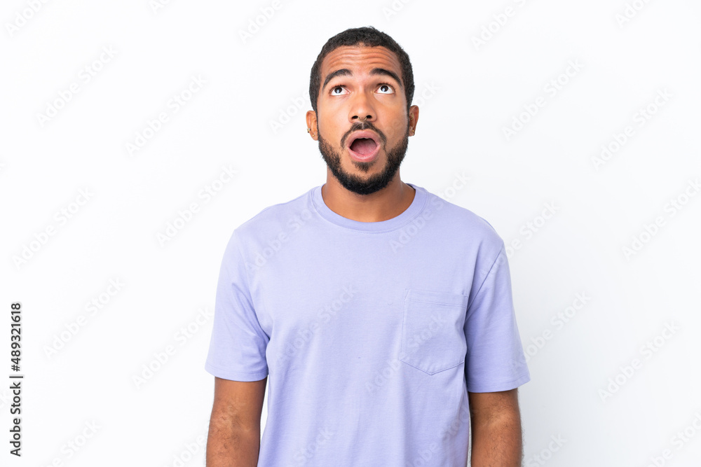 Young Ecuadorian man isolated on white background looking up and with surprised expression Young Ecuadorian man isolated on white background looking up and with surprised expression