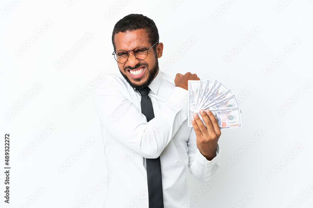 Young business latin man taking a lot of money isolated on white background suffering from pain in shoulder for having made an effort Young business latin man taking a lot of money isolated on white background suffering from pain in shoulder for having made an effort