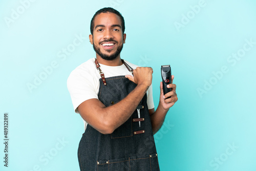 Young hairdresser latin man isolated on blue background proud and self-satisfied