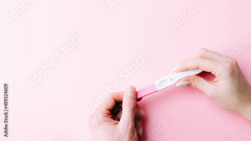 Pregnancy test positive. Female hand hold positive pregnant test with silk ribbon on pink background. Medical healthcare gynecological  pregnancy fertility maternity people concept.