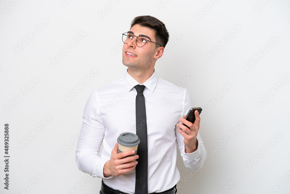 Business caucasian man isolated on white background holding coffee to take away and a mobile while thinking something Business caucasian man isolated on white background holding coffee to take away and a mobile while thinking something