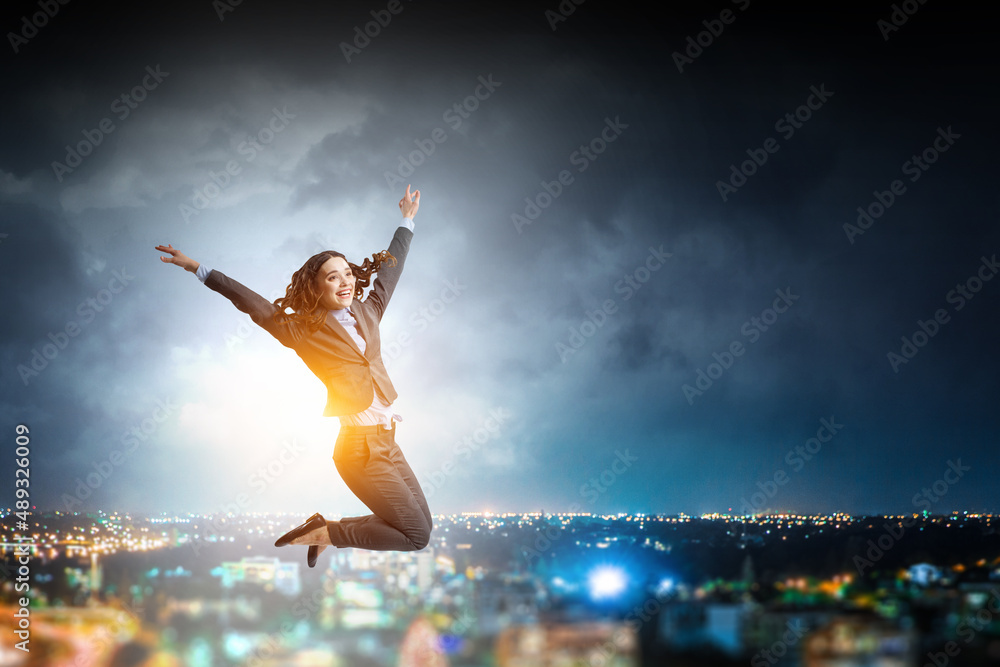 Portrait of energetic businesswoman jumping in open air