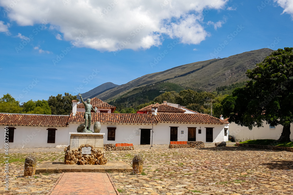 Monument and traditional buildings at Plaza Mayor of Villa de Leyva, Colombia, blue sky, white clouds and mountains in background
Monument and traditional buildings at Plaza Mayor of Villa de Leyva, Colombia, blue sky, white clouds and mountains in background