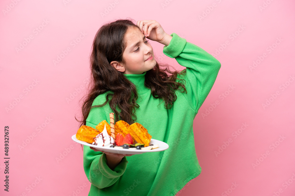 Little caucasian girl holding waffles isolated on pink background having doubts and with confuse face expression Little caucasian girl holding waffles isolated on pink background having doubts and with confuse face expression