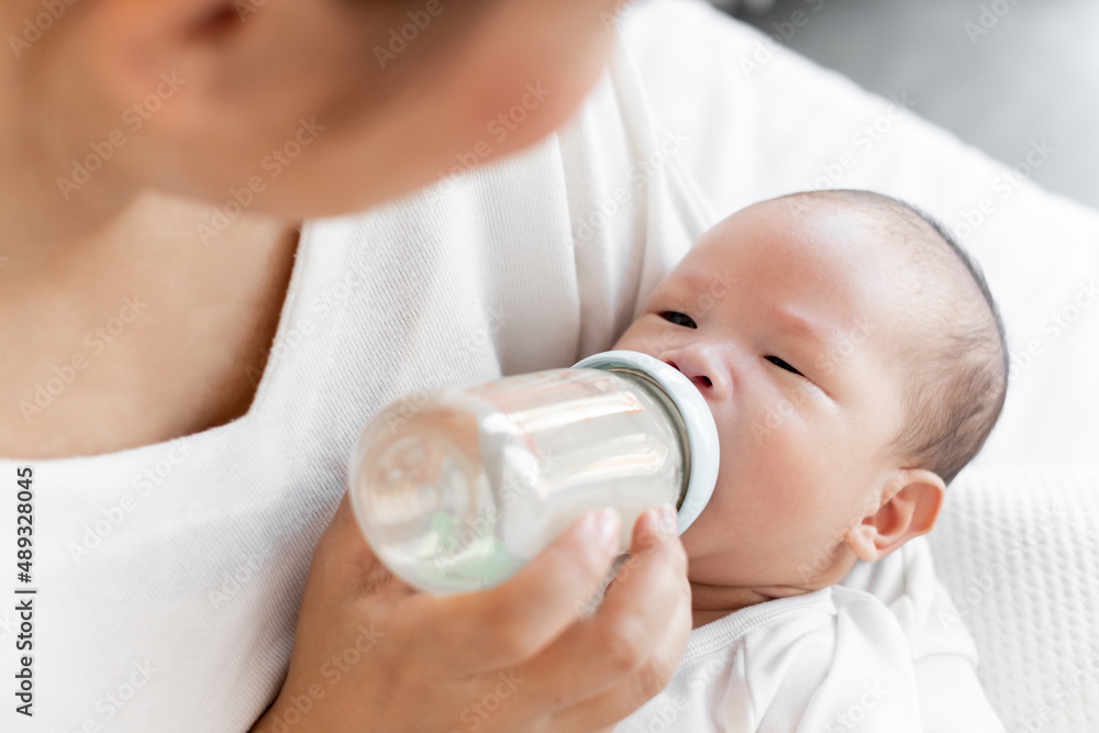 Mother breast feeding milk to Asian newborn baby on white bed Mother breast feeding milk to Asian newborn baby on white bed