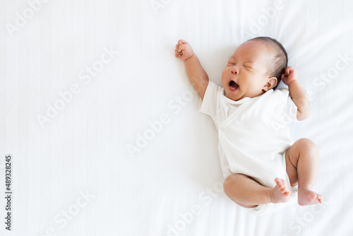 Fototapeta Portrait of Asian newborn baby in white cloth on bed funny pos