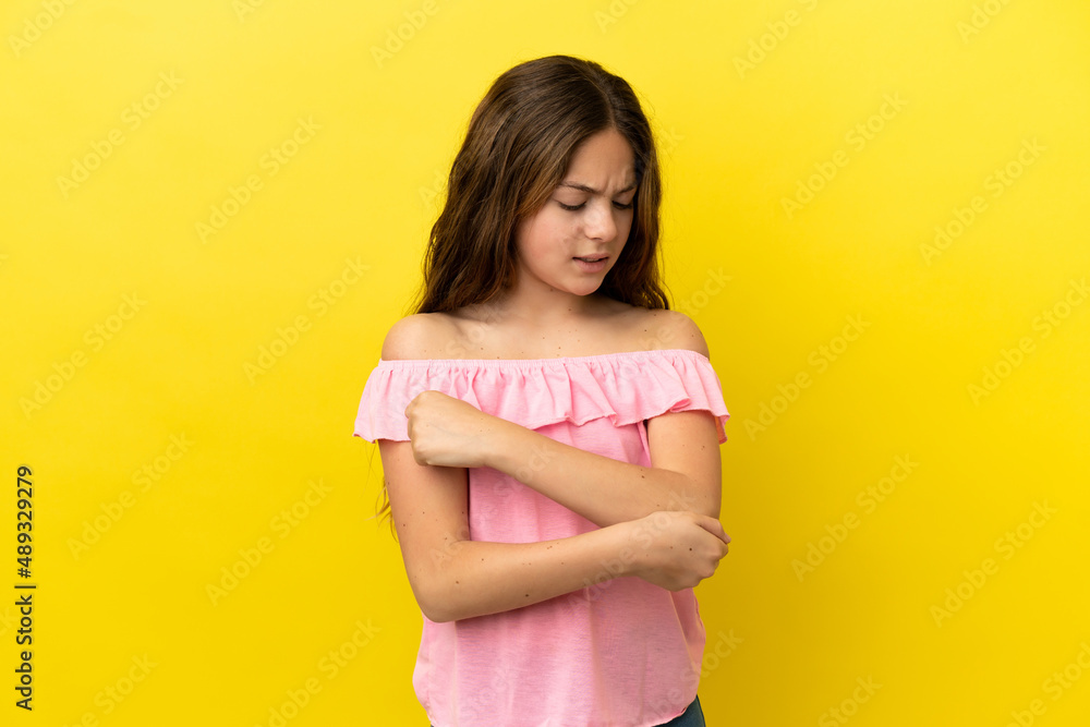 Little caucasian girl isolated on yellow background with pain in elbow Little caucasian girl isolated on yellow background with pain in elbow
