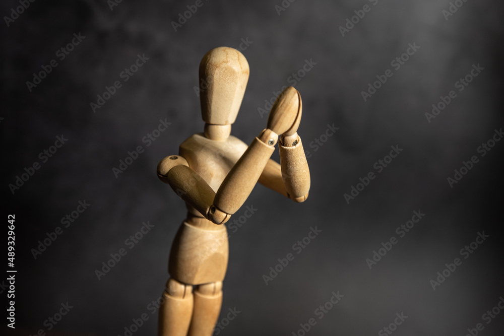 wooden figure of a person praying, dark background wooden figure of a person praying, dark background