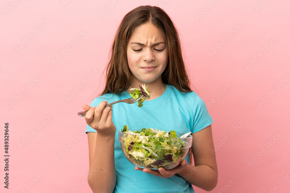Little caucasian girl isolated on pink background holding a bowl of salad with sad expression Little caucasian girl isolated on pink background holding a bowl of salad with sad expression