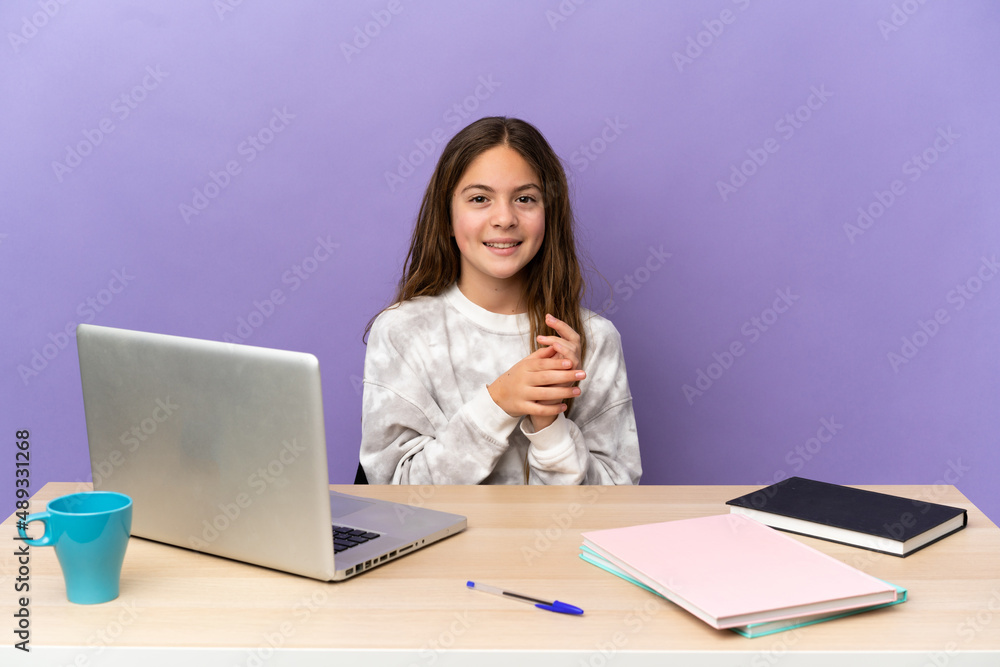 Little student girl in a workplace with a laptop isolated on purple background applauding Little student girl in a workplace with a laptop isolated on purple background applauding
