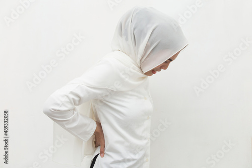 Sick asian muslim woman having a stomach ache, low back pain and waist lumbar pain 