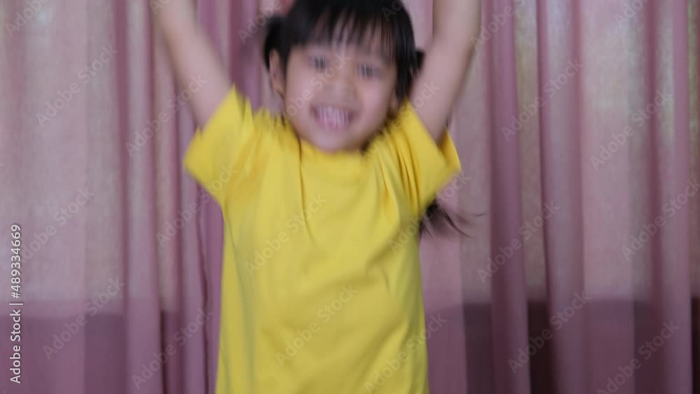Portrait of a cute little girl in a yellow t-shirt jumping happily at home. Active girls feel freedom. Concept of facial expressions and gestures Portrait of a cute little girl in a yellow t-shirt jumping happily at home. Active girls feel freedom. Concept of facial expressions and gestures