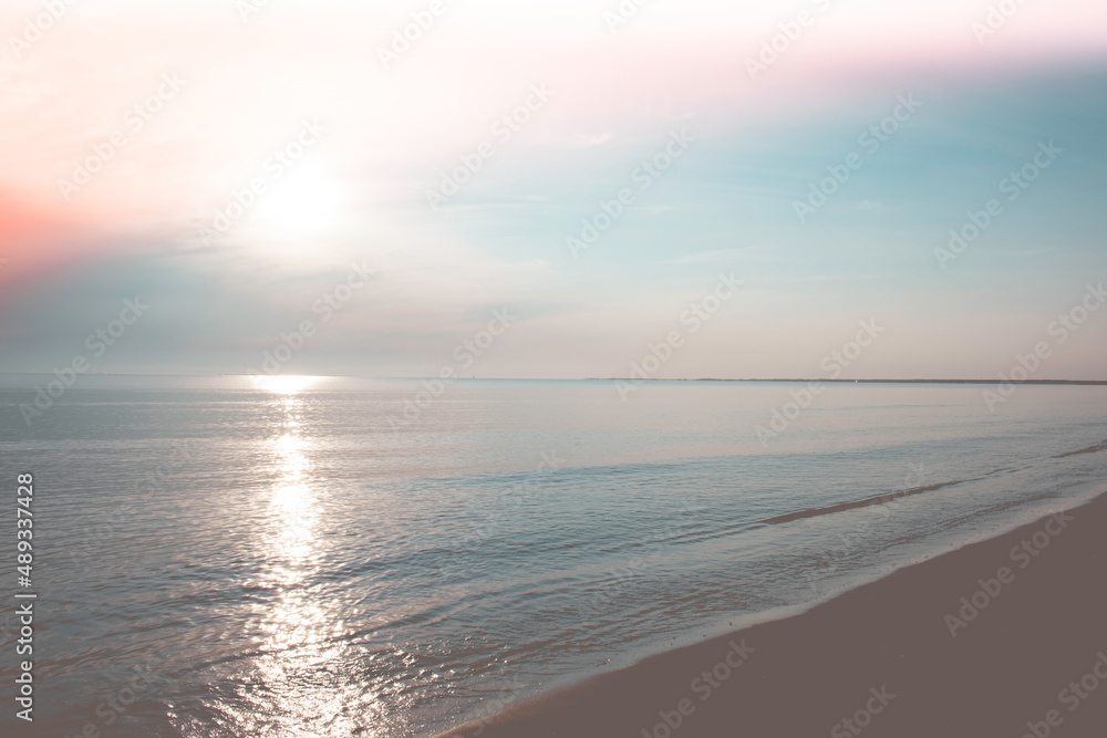 Fototapeta premium Beach with calm ocean under beautiful pastel sunrise.