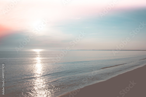 Beach with calm ocean under beautiful pastel sunrise. photo