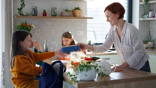 Mother of three little children preparing breakfast and lunch boxes in kitchen at home. photo