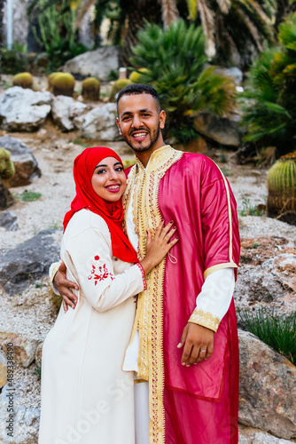 three quarter length image of a cute arab couple dressed with traditional clothes embraced in a cactus garden