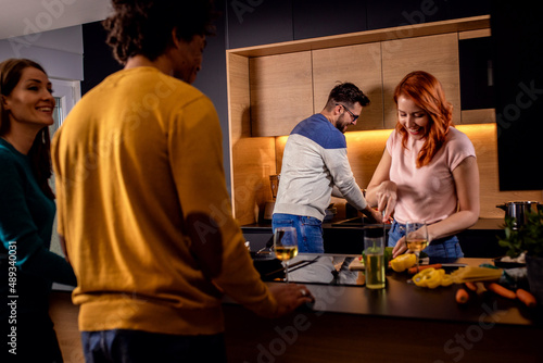 Group of friends preparing vegetarian meal in a kitchen at home.