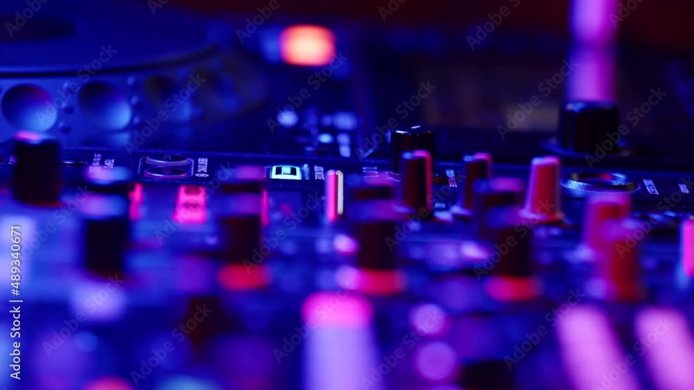 DJ sound control console for mixing dance music in disco club, closeup. DJ hands twist and press the buttons on remote control DJ sound control console for mixing dance music in disco club, closeup. DJ hands twist and press the buttons on remote control