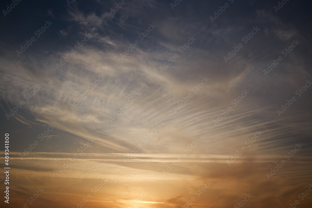 Sunset sky, clouds illuminated by the sun. Contrails and feather clouds. Sunset sky, clouds illuminated by the sun. Contrails and feather clouds.