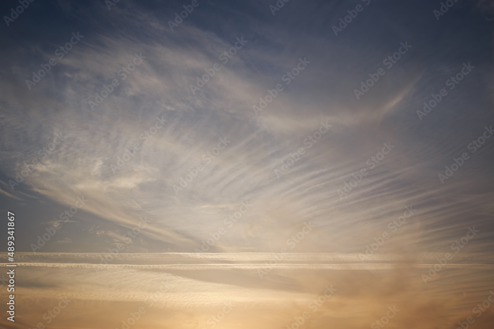 Sunset sky, clouds illuminated by the sun. Contrails and feather clouds. 