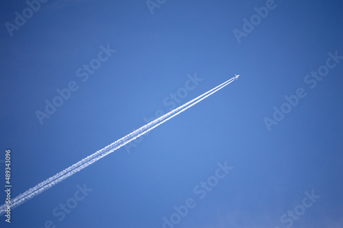 Airplane with jet trail on blue skies
