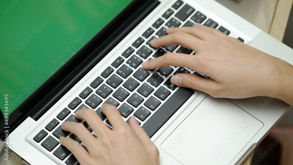 Close up of woman's hands typing on laptop with green screen, using laptop for working. Close up of woman's hands typing on laptop with green screen, using laptop for working.