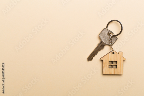 Keys with house-shaped keychain on color background