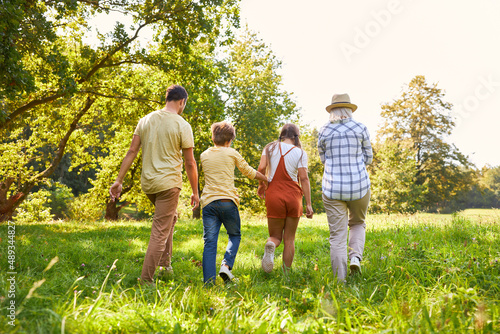 Family with two children walking on a green meadow on summer vacation