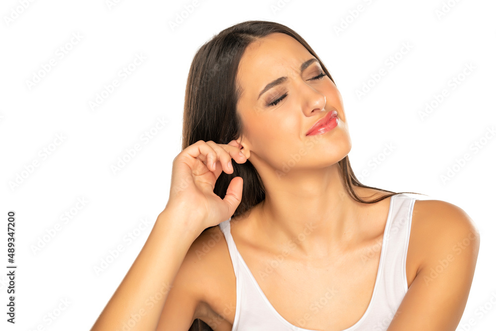 young woman on white background with emotions of irritation scratches her ear with finger young woman on white background with emotions of irritation scratches her ear with finger