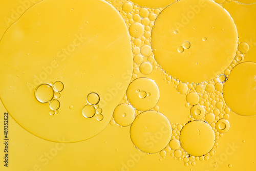 Golden yellow abstract oil bubbles or face serum background. Oil and water bubbles macro photography. photo