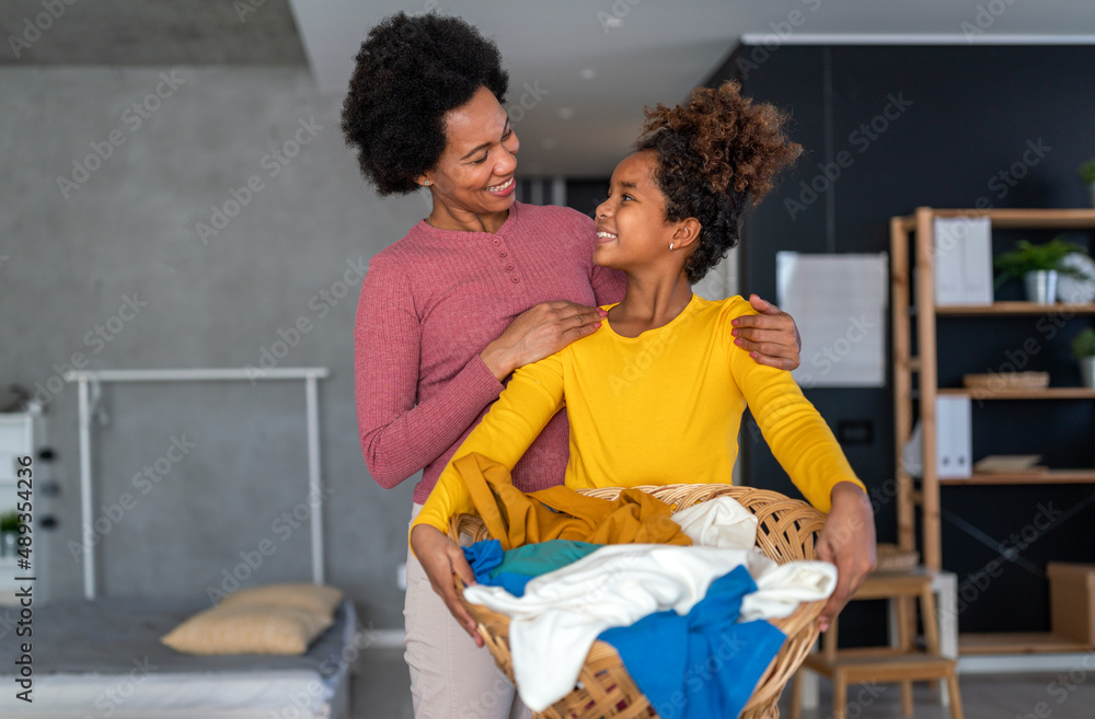Happy black daughter helping mother do household and domestic chores together