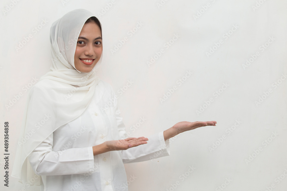 Happy young asian muslim woman pointing with fingers to different directions isolated on white background Happy young asian muslim woman pointing with fingers to different directions isolated on white background