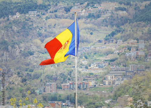 Flag of Andorra on the background of mountains and houses.